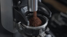 A steady slow motion top angle close shot of coffee powder falling from a coffee grinder into portafilter of the coffee machine - Powered by Shutterstock - Get 15% off with code: PIKWIZARD15