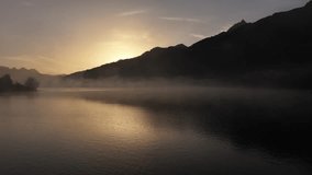 A static image capturing a beautiful sunrise over a misty lake, with orange sun rays piercing through the fog and reflecting softly on the water, creating a tranquil and warm ambiance. - Powered by Shutterstock - Get 15% off with code: PIKWIZARD15