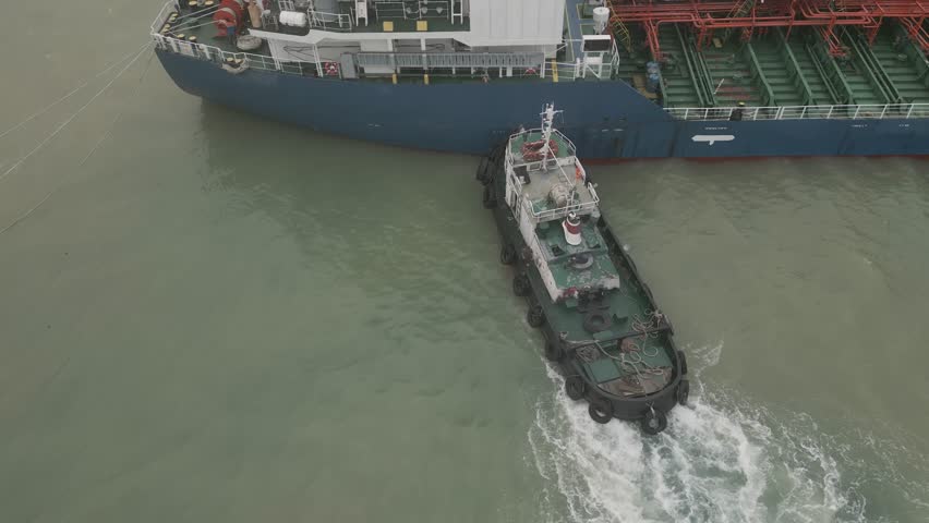 tugboat pushes tanker helps to park
