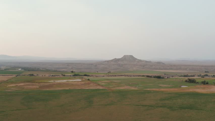 Drone shot tracking backwards. Wyoming farmlands with a Bluff in the distance.