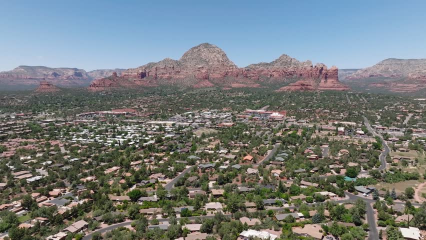Sedona, arizona with red rock mountains, green suburbs, and clear blue skies , aerial view