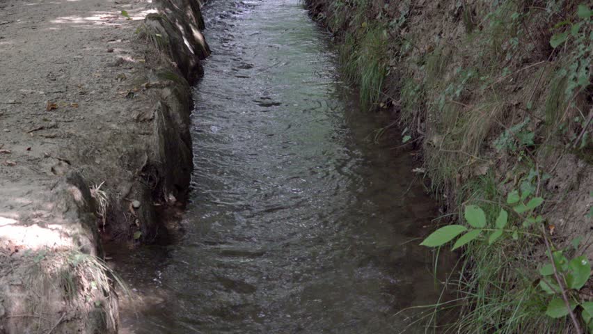 Close-up of a part of an irrigation channel designed to transport water from a source to various use. A hiking trail leads along the irrigation canal