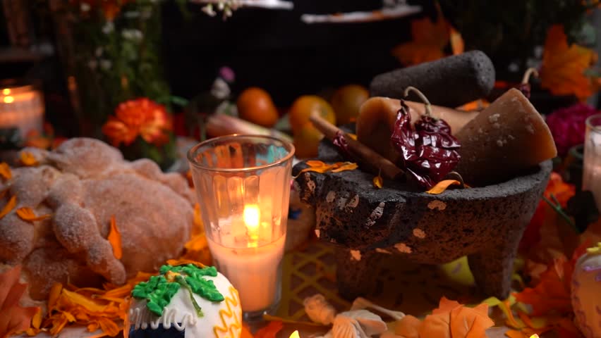 Bread and burning candle offering on Day of Dead altar with marigold