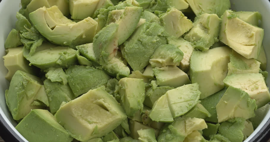 Avocado pieces in an enameled bowl. Table spin.