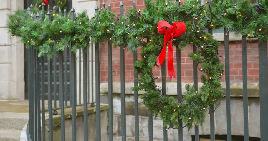 Christmas wreath with a red bow draped on fence. Closeup shot. 4k.