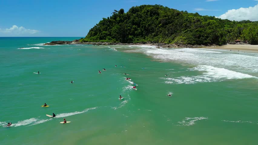Aerial follows two surfers riding a wave at Praia da Engenhoca beach in Bahia