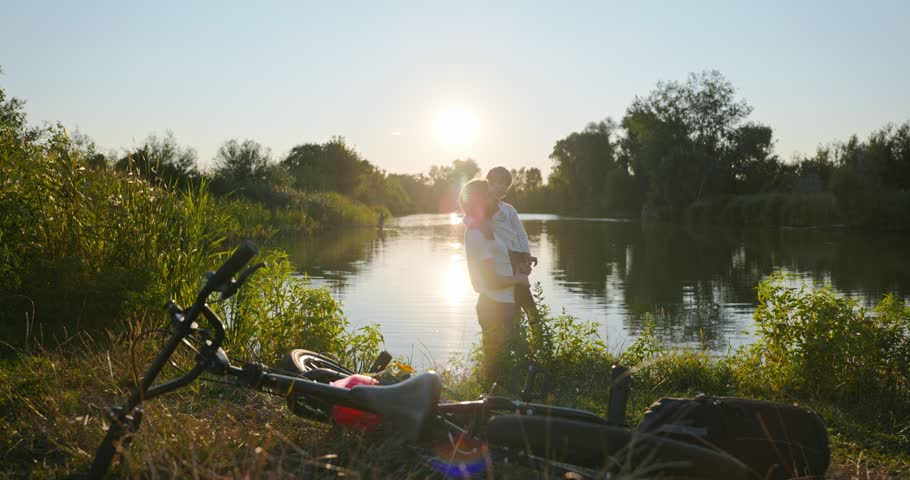 Father with Son Spend Together Happy Evening Time on Nature Watching Sunset Above Lake. 4K 10-bit