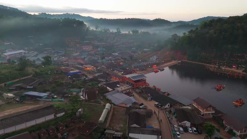 Aerial dolly establishing of Ban Rak Thai, Northern Thailand, lush lmisty andscapes and scenic lake surrounded by homes