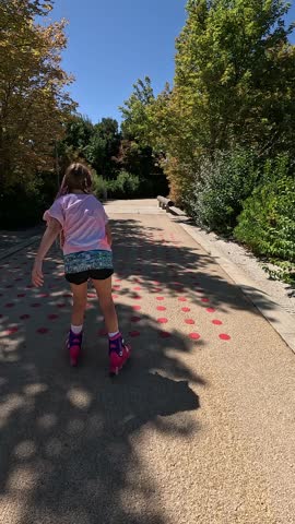 Vertical video following a girl skating on a paved pedestrian path in a forest next to the river in the city of Madrid, Spain