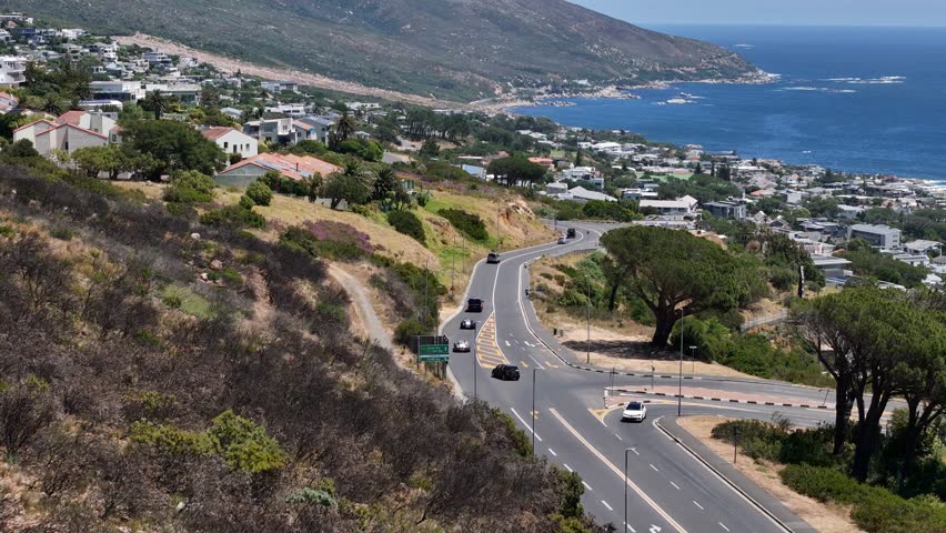 Drone clip of cars driving to and from Camps Bay Cape Town which is a scenic neighbourhood surrounded by ocean and mountains