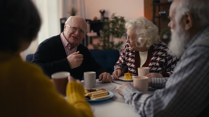 Group of senior people share the latest news and drink tea in a retirement home