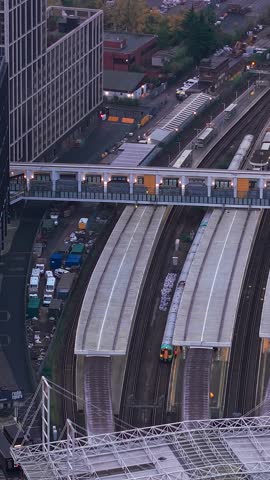 Vertical aerial view circling above Croydon train station bridge crossing multiple platforms