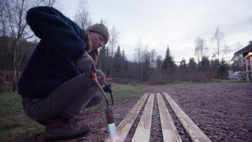 Handywoman uses blowtorch to char planks in traditional technique, slider shot