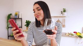 Young happy pretty woman drinking red wine while using smart phone in modern kitchen at home, waiting her food to be cooked - Powered by Shutterstock - Get 15% off with code: PIKWIZARD15