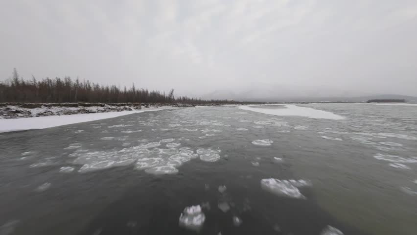 Witness the breathtaking icy rivers and tranquil forests of Yakutia as a drone glides above the frozen terrain. Experience the stunning natural beauty of this remote region.