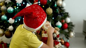 A Child Wearing a Santa Hat Holding a Santa Claus Decoration in Front of a Christmas Tree - Close Up - Powered by Shutterstock - Get 15% off with code: PIKWIZARD15