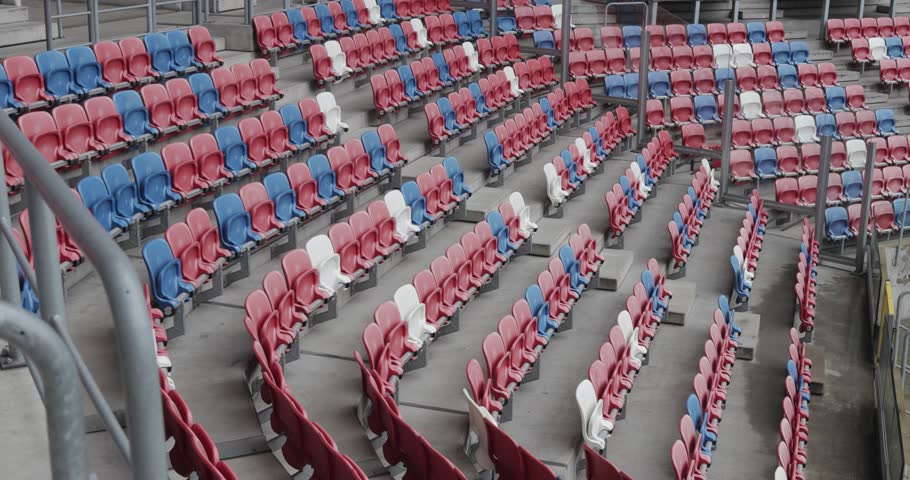 Dynamic shot of empty stands in a modern football stadium of Górnik Zabrze with red, blue, and white seats in Poland, 4K