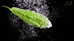 Bitter gourd dropping into aquarium in slow motion, isolated on black background. - Powered by Shutterstock - Get 15% off with code: PIKWIZARD15