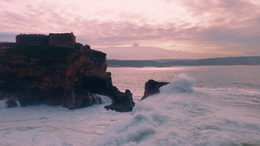 Majestic Slow Motioned Waves Crashing Beneath a Sunset-Lit Fortress