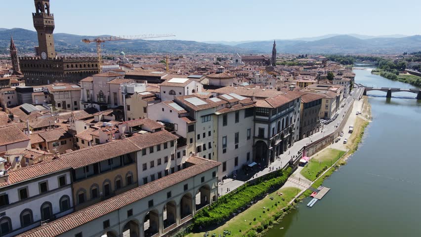 Drone ascends over Florence, revealing historic rooftops, bright sunny panorama