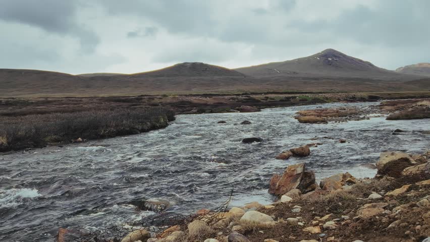 A river streaming through a desert, with terrain background under dramatic cloudy sky in Skardu, Pakistan