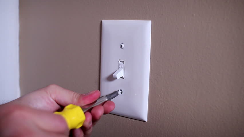 An electrician repairs a wall light switch.