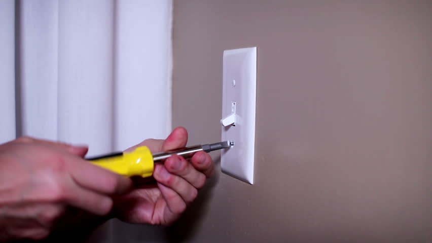An electrician repairs a wall light switch.