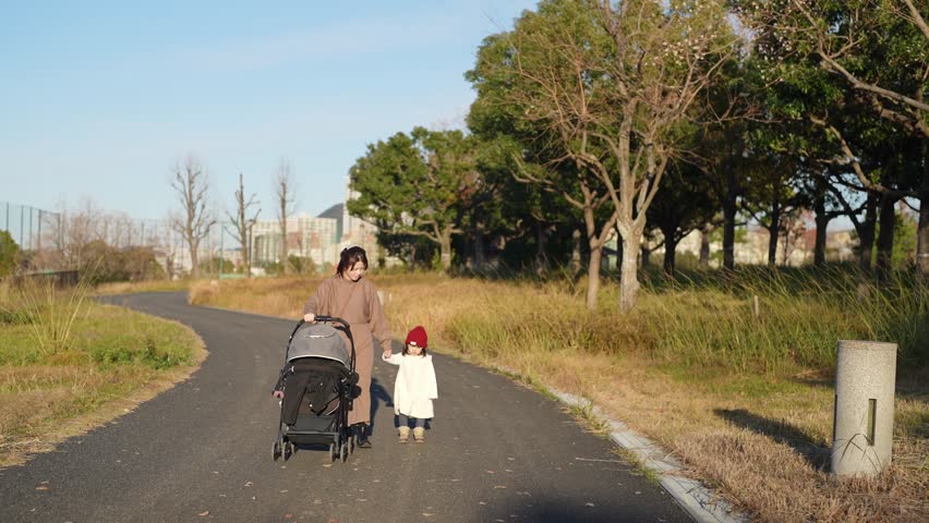 In December 2024, a Japanese parent and child, a 3-year-old girl and her 30s mother, spend time in a lush park in Higashi Ward, Fukuoka City, Fukuoka Prefecture. Slow motion footage.
