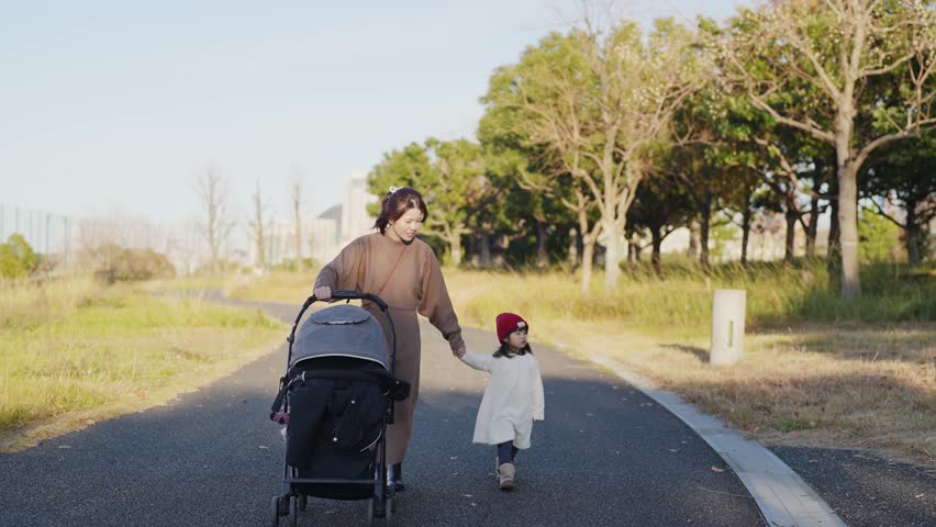 In December 2024, a Japanese parent and child, a 3-year-old girl and her 30s mother, spend time in a lush park in Higashi Ward, Fukuoka City, Fukuoka Prefecture. Slow motion footage.