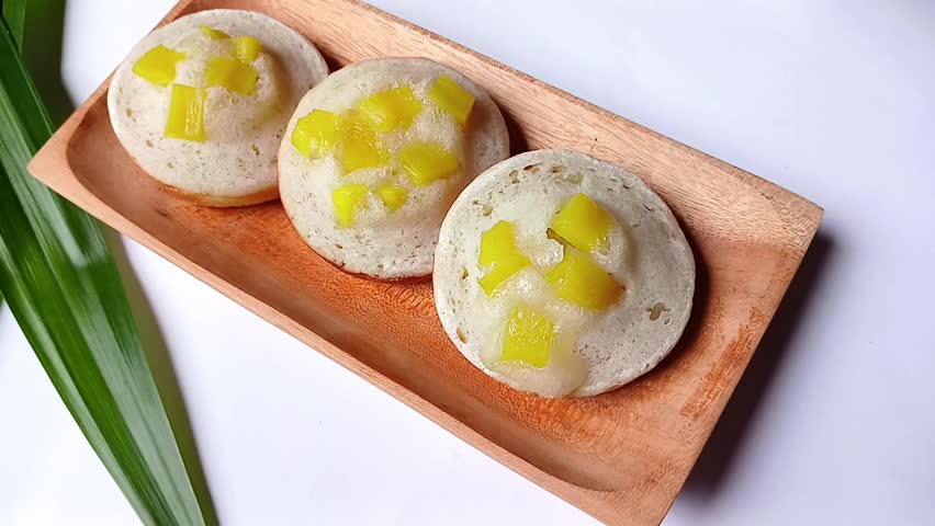 Delicious apem cake with jackfruit topping in wooden plate isolated on white background. Apem or apam is traditional Indonesian cake that has sweet taste and soft texture