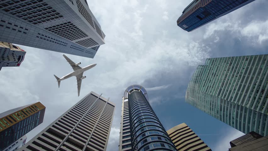 Airplane flight over the business center of skyscrapers. Bottom view of skyscrapers with a flying plane at sunset in the evening, business district. Success business concept. 3D animation 4k UHD
