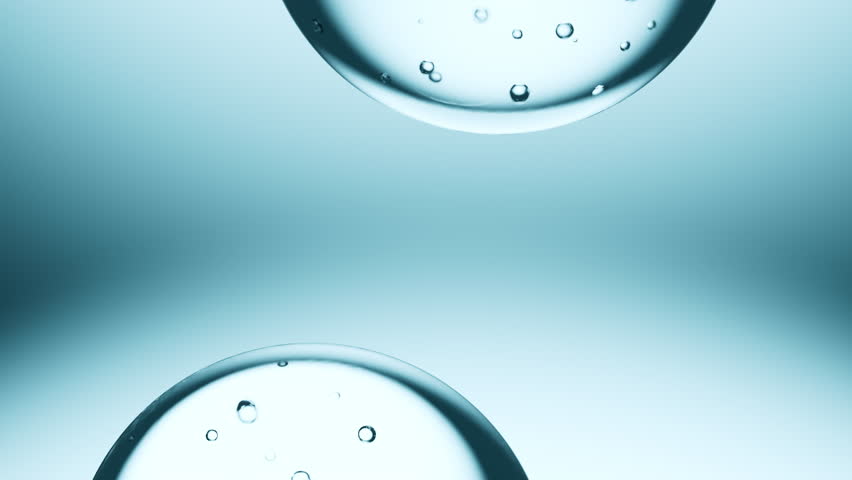 Macro shot of drops of pure fresh melt mountain water with tiny air bubbles, the drops are moving and merging into a large water sphere on a bright light blue background