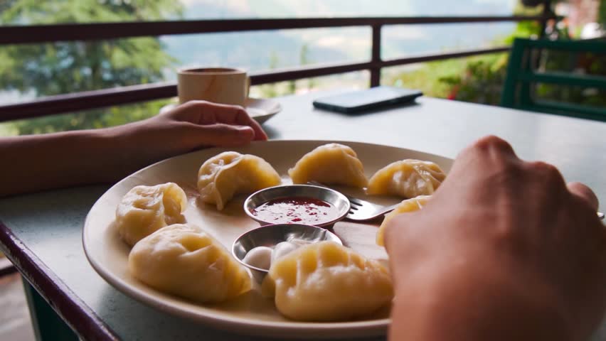 Closeup Shot of girl Picking Momo Dumpling on Plate. Plate of Momo food from Nepal. Tibetan momo Street food in Manali, Himachal Pradesh, India. 