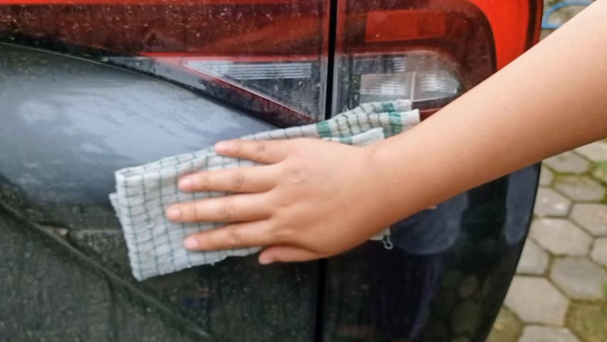 Wipe the rear body of Toyota car with a cloth 