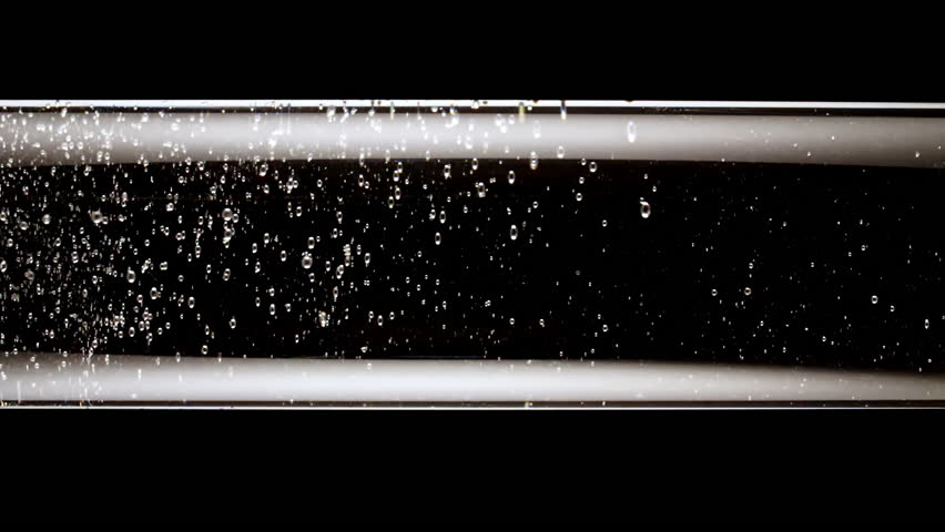 Macro shot of fine air bubbles rising in water in glass test tube on black background. Effervescent tablet aspirin. The medicine concept, health care, treatment. Slow motion.