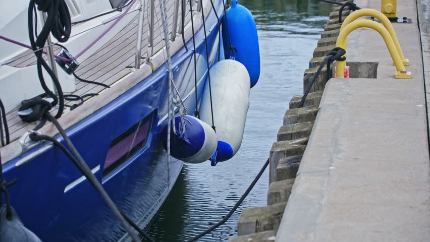 Sea Sailing Yacht Moored at Marina with Protective Rubber Fenders Hanging Between Side and Concrete Wharf Quay