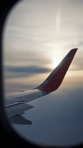Traveling and tourism, view from passenger window of modern plane, vertical video. Transportation between countries and cities, fascinating cloudscape, airplane wing and sun, enjoy safety flight