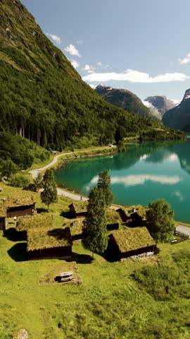 Nestled between towering mountains, traditional grass-roofed homes coexist harmoniously with Norways breathtaking nature, revealing a peaceful lakeside setting, Lovatnet Norway