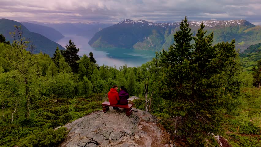 Two friends enjoy stunning vistas over Norways majestic fjords, surrounded by lush greenery. The serene landscape offers a perfect escape into natures beauty. LustraFjord Molden Hike Norway
