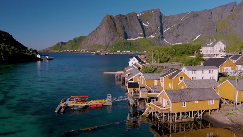 Enjoy the vibrant hues of traditional houses by the water, surrounded by stunning mountain landscapes in Norway. Sakrisoy Lofoten