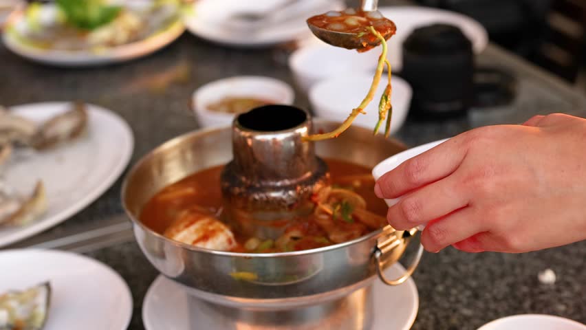 Ladling soup into a bowl at a table