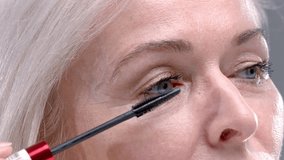 Close up: old woman paints her eyelashes with mascara. Senior female puts mascara on her eyes, expressive blonde look. Carefree pensioner portrait, good eyesight after vision correction. Elderly lady - Powered by Shutterstock - Get 15% off with code: PIKWIZARD15