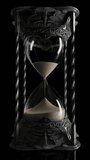 A static view of an ornate antique brass hourglass sand timer with sand falling on a dark black background  - Powered by Shutterstock - Get 15% off with code: PIKWIZARD15