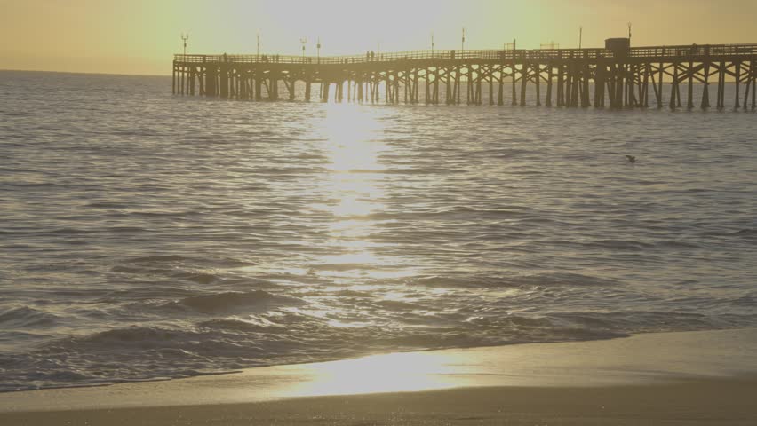 A calm sunset at Long Beach Pier, California, with waves gently rolling ashore