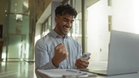Young man with beard using smartphone smiling in modern office with laptop on desk - Powered by Shutterstock - Get 15% off with code: PIKWIZARD15