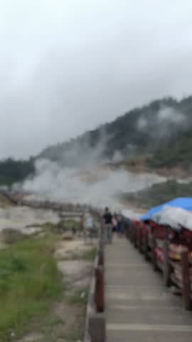 blurry portrait of distant appearance of a crater filled with hot sulfur emitting a lot of pungent gas vapor there is a wooden bridge road, out of focus, abstract