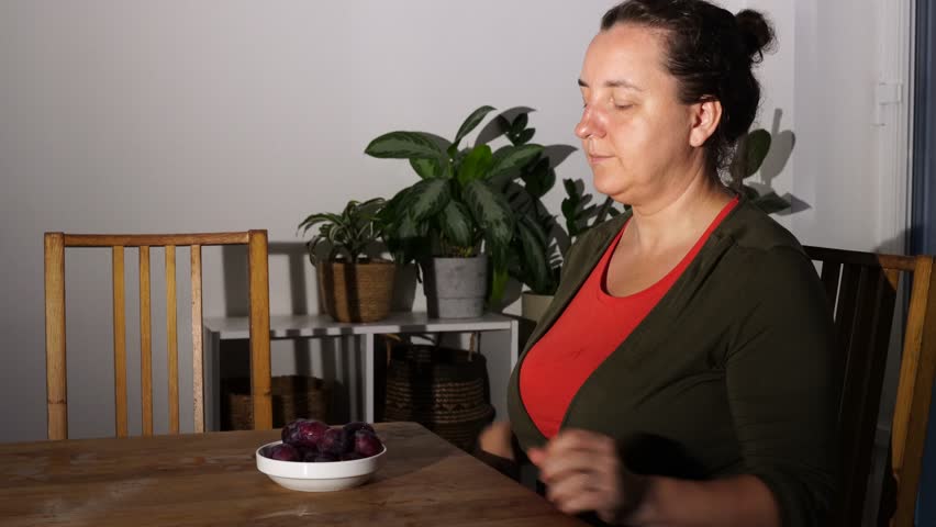 Woman eats plum at home