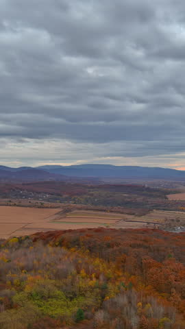 Overlooking picturesque mountains forest hills landscape, fall colors blanket trees fields under cloudy sky.