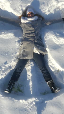 AERIAL: Flying above the woman making snow angel in winter