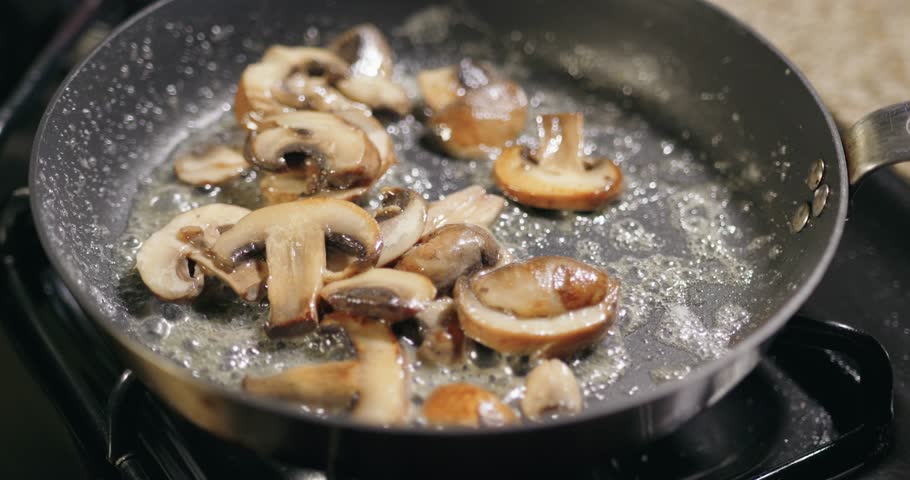 Cooking sautéed mushrooms in a skillet on a stove 